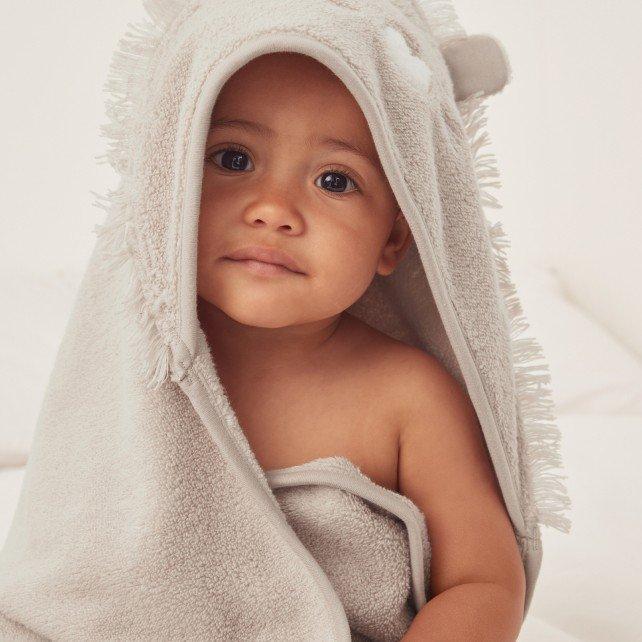 a baby wrapped in a towel sitting on a bed