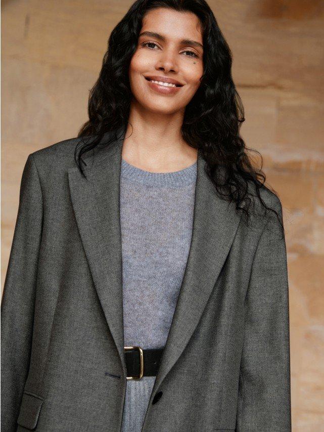 a woman in a gray suit and a black belt