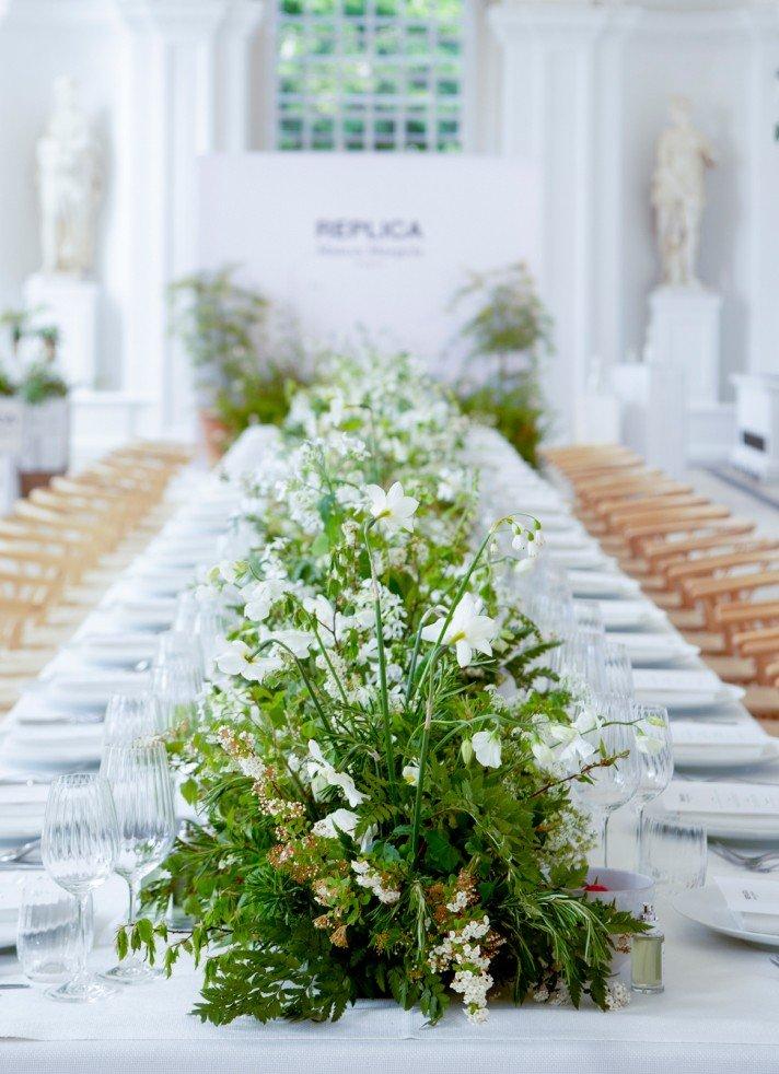 a long table with white table cloth and white flowers