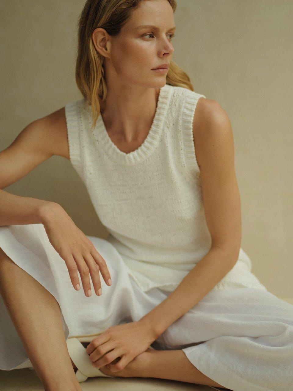 a woman in a white top sitting on a stool