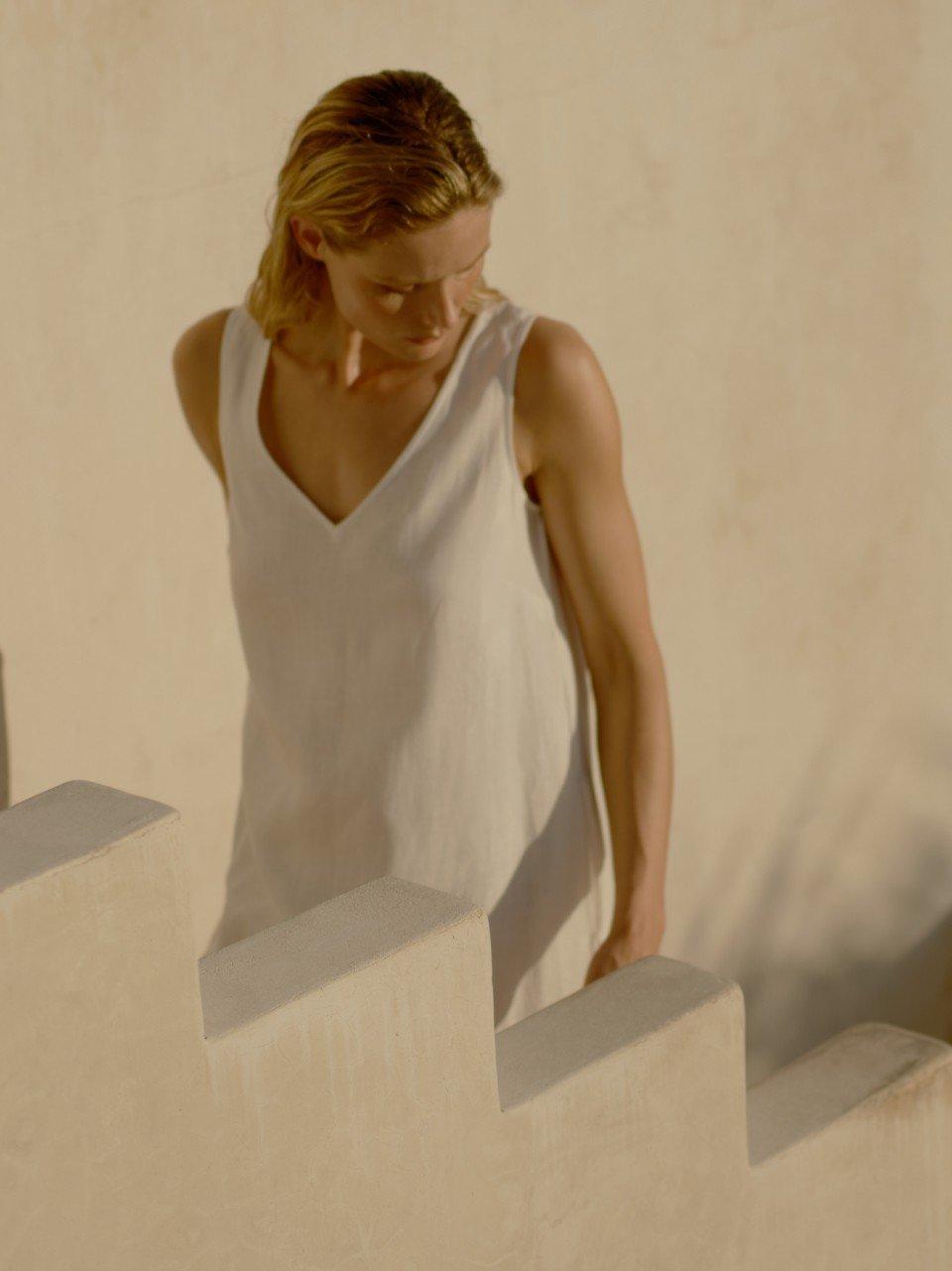 a woman in a white dress standing on a set of stairs