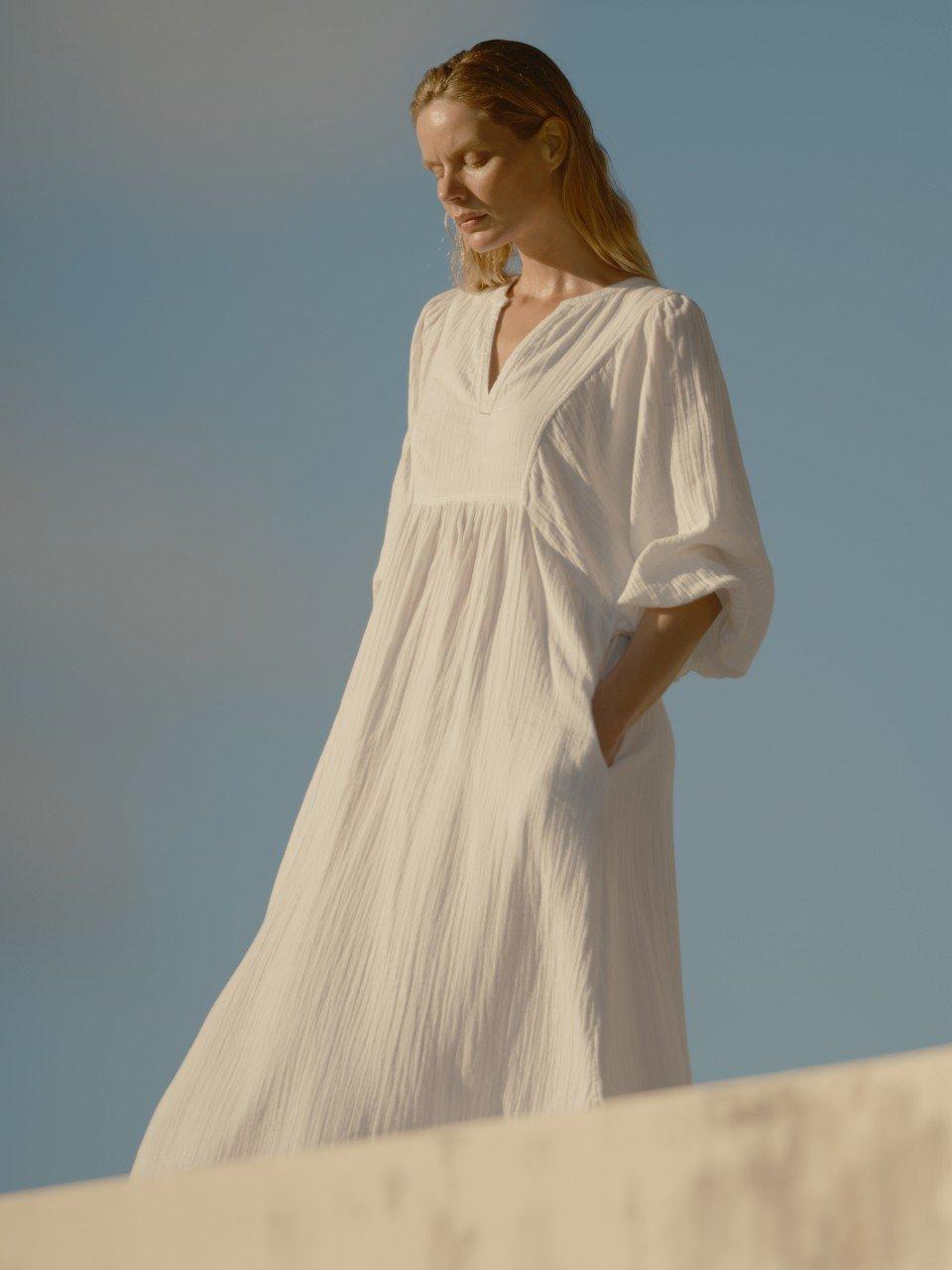 a woman in a white dress standing on a ledge