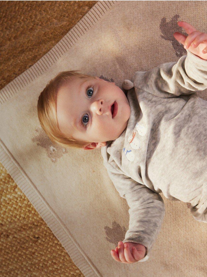 a baby laying on a rug with a toy in front of him