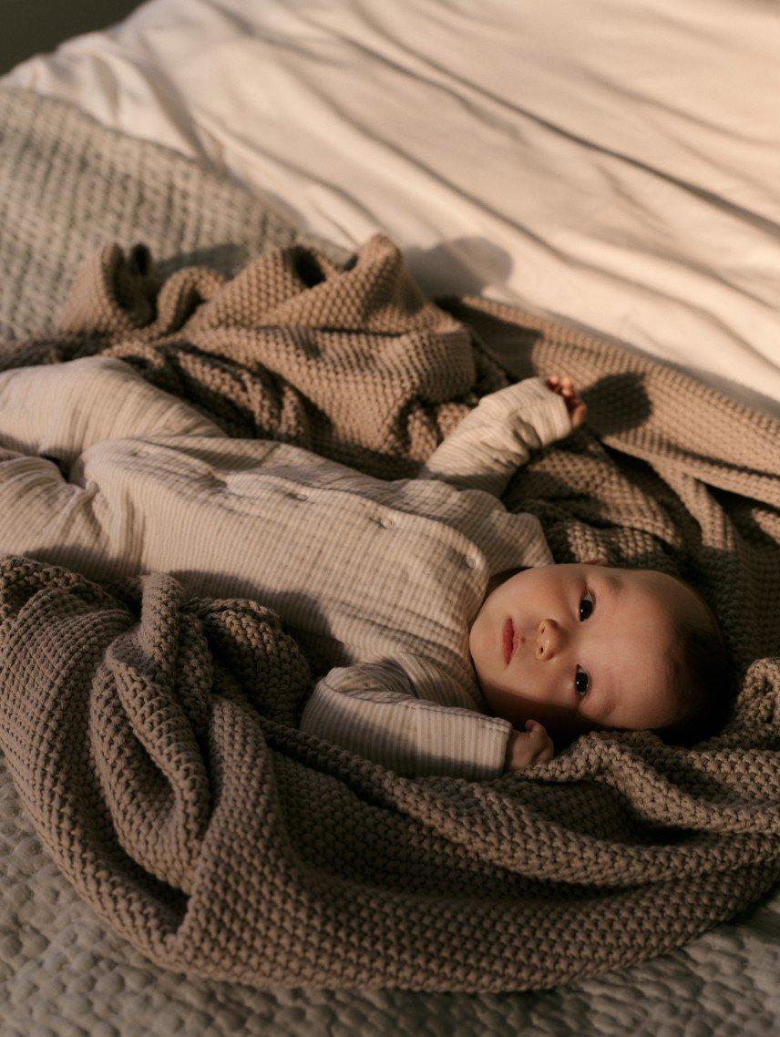 a baby laying on a blanket on a bed