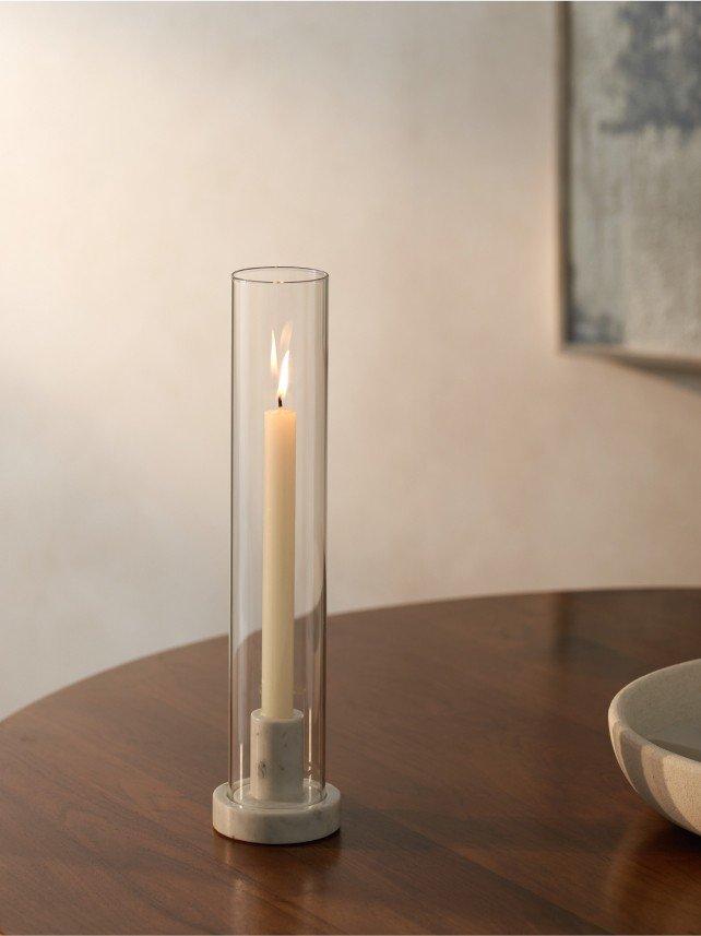 a candle sitting in a glass cylinder on a wooden table