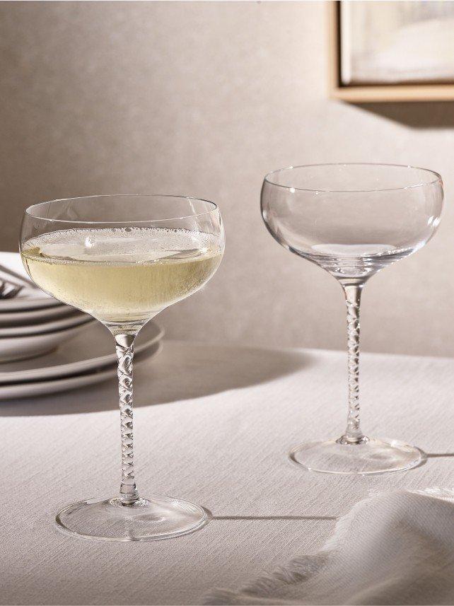 two wine glasses on a table with plates and silverware