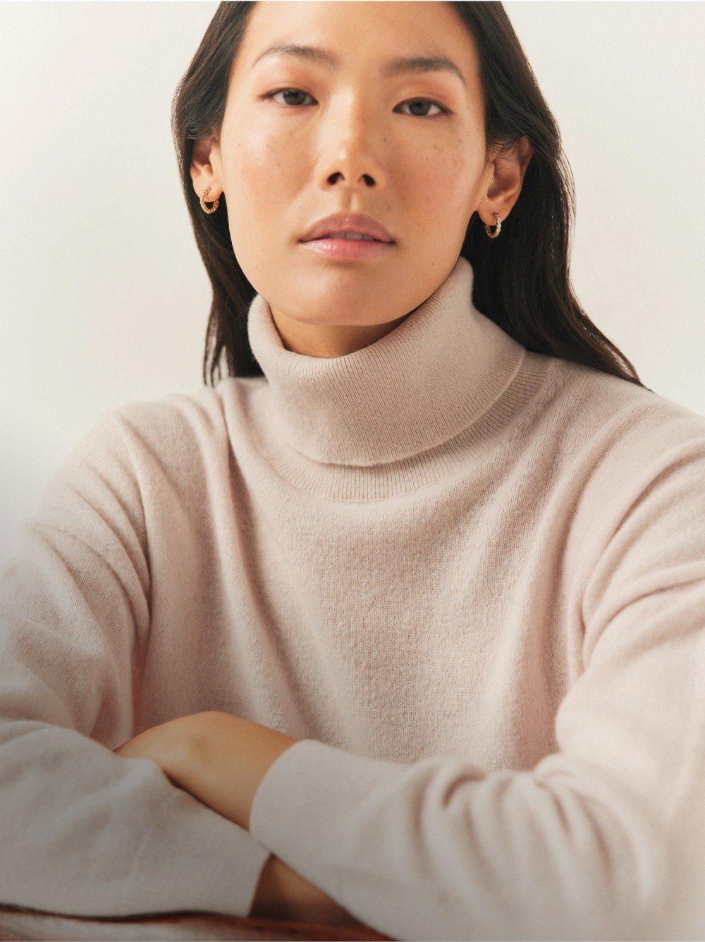 a woman sitting on the floor wearing a grey sweatshirt and pants