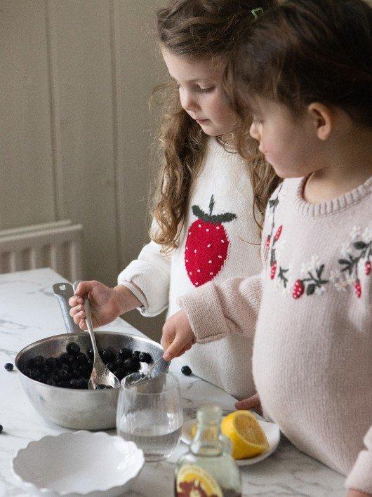 two young girls are preparing a meal in a kitchen