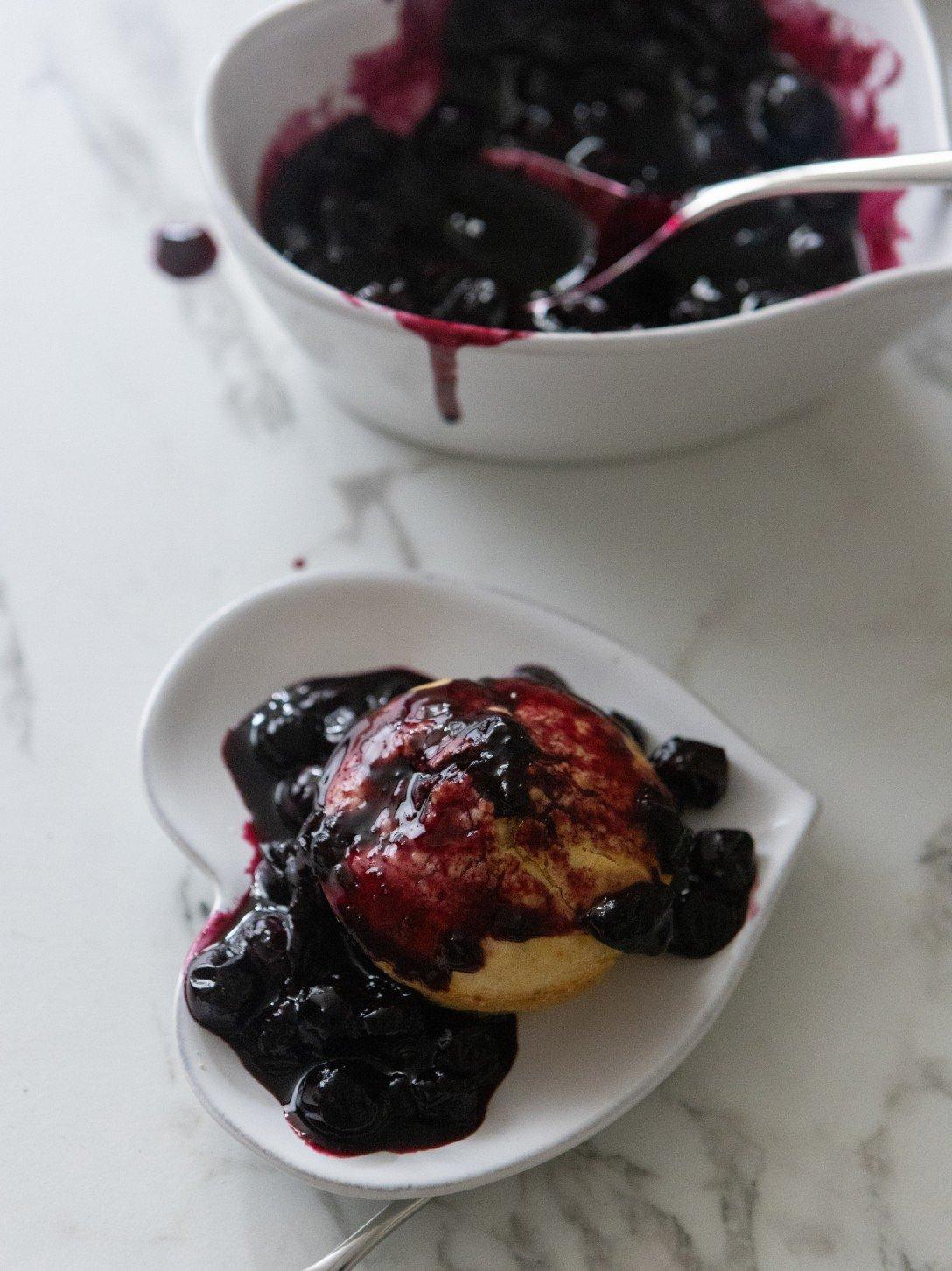 a heart shaped plates with blueberry sauce and a biscuit