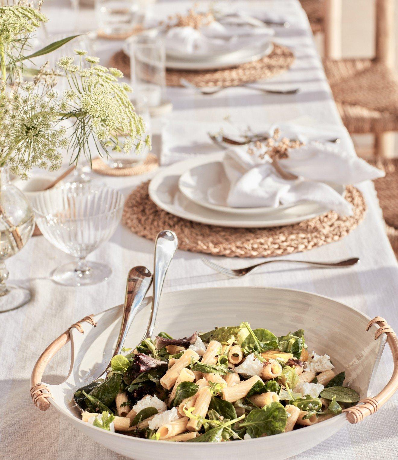 a table with a bowl of salad and silverware on it