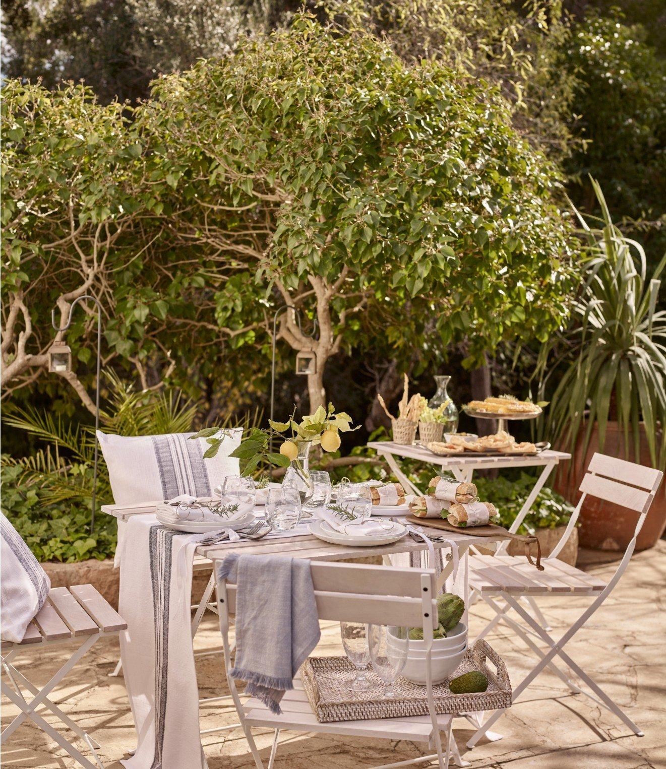 a table and chairs set up outside in a garden setting