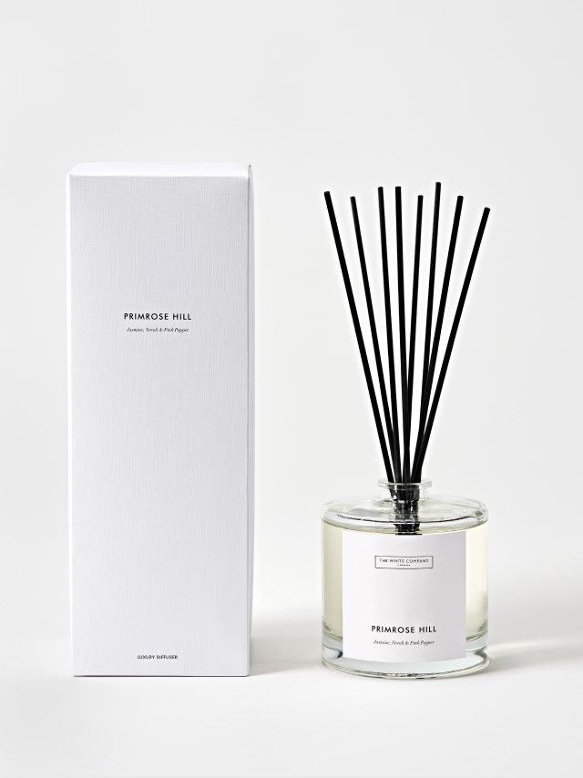 a bottle of perfume sits on a plate next to some blackberries