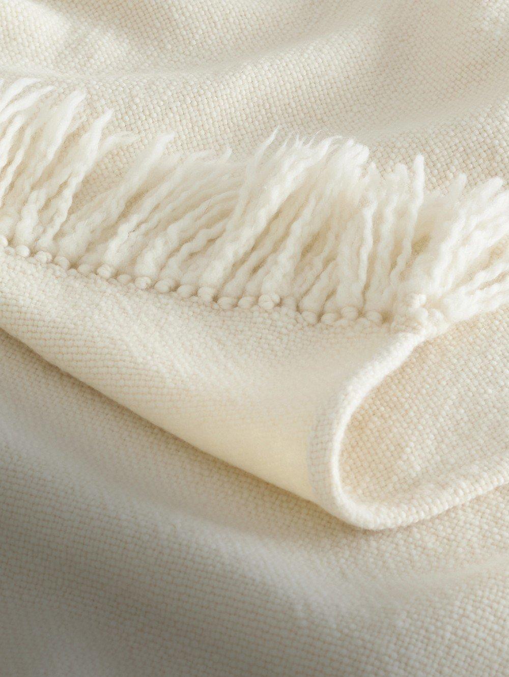 a close up of a white blanket with fringes on it