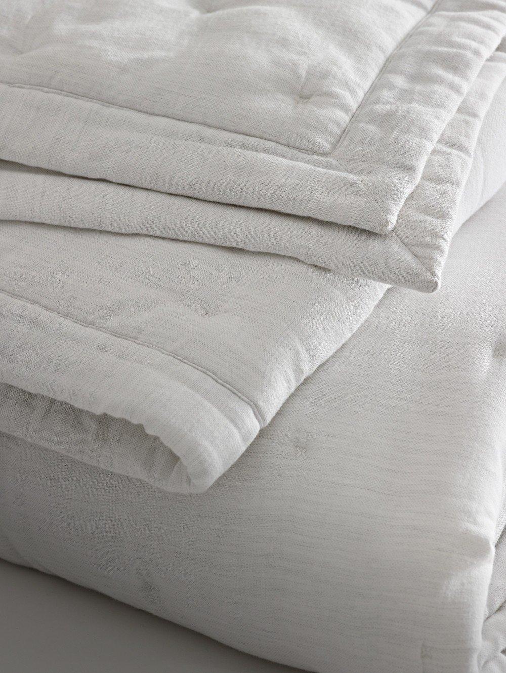 a close up of a white blanket folded up on a bed