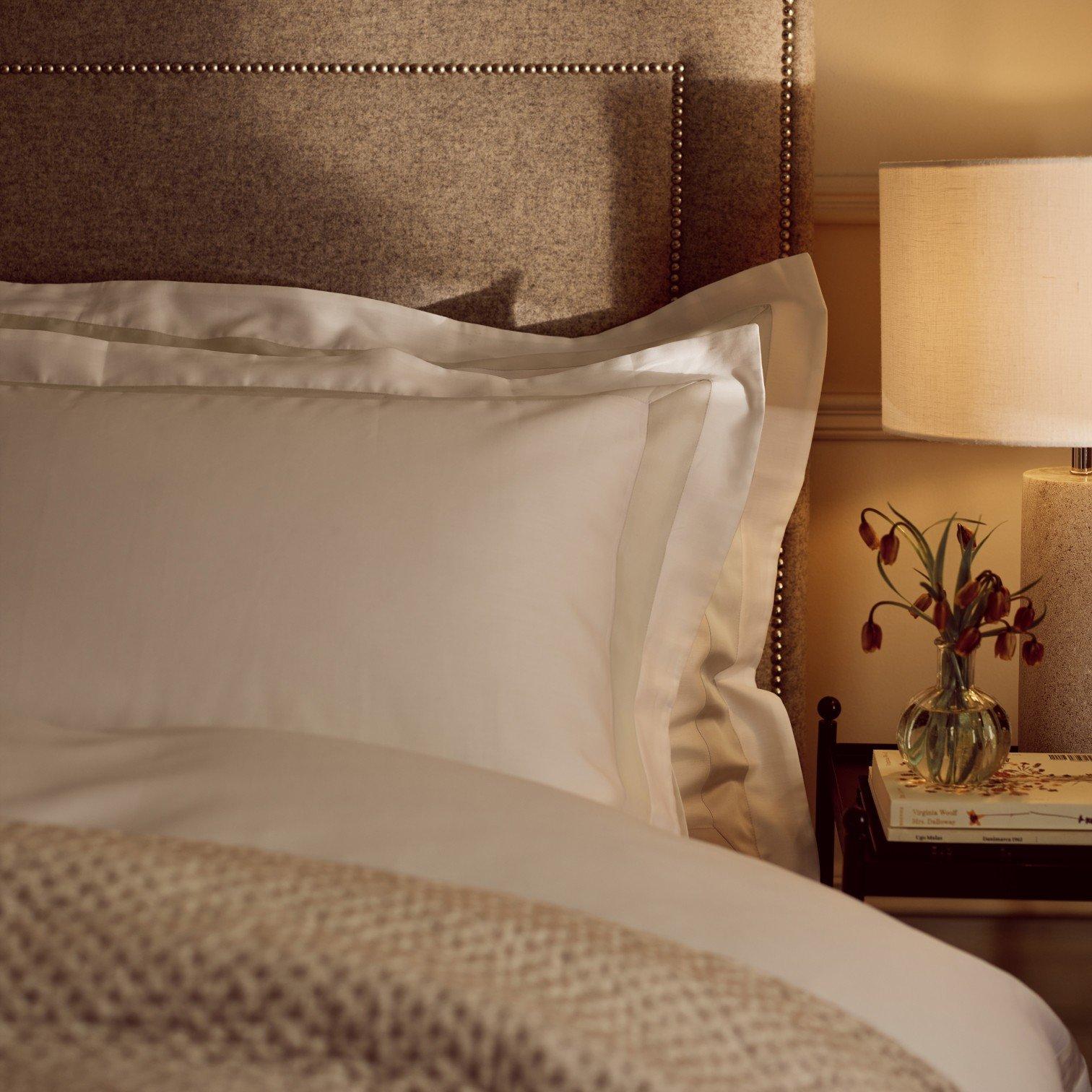 a bed with white sheets and pillows next to a nightstand