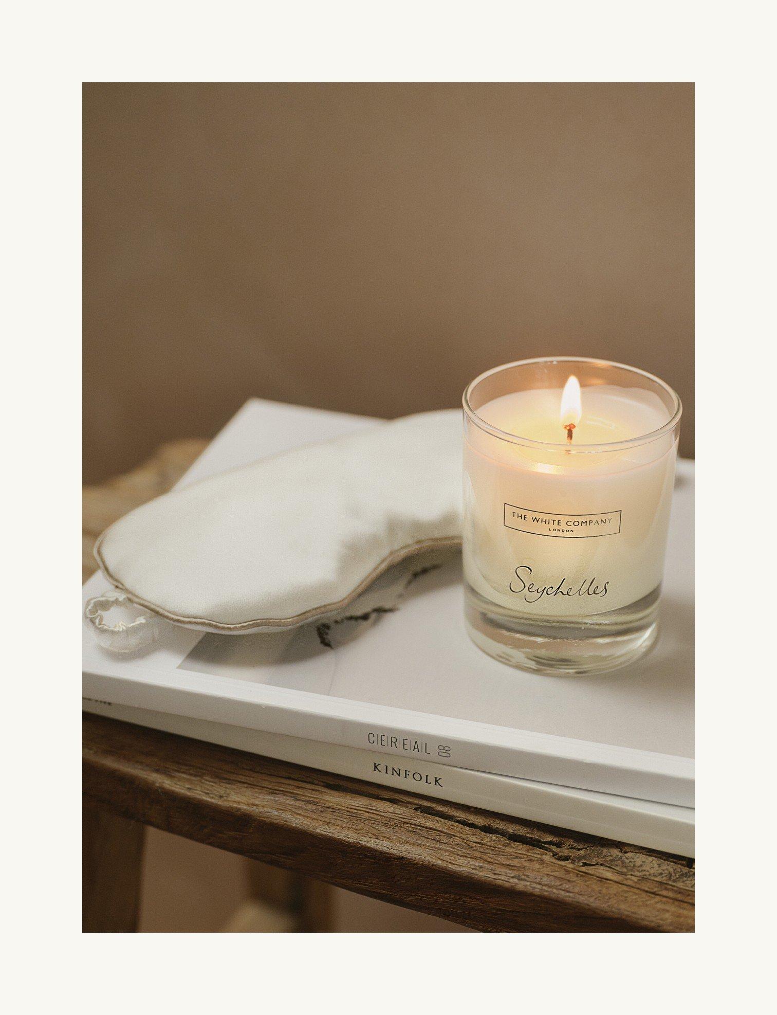 a candle sits on a table next to a book and a mask