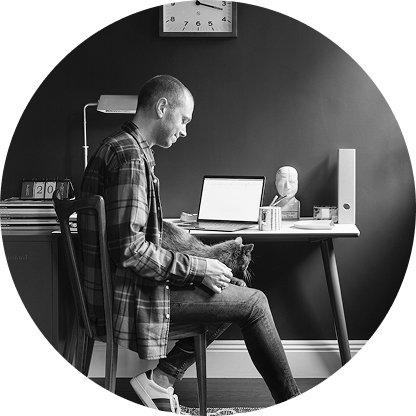 a man sitting in chair with a cat on his lap at a desk