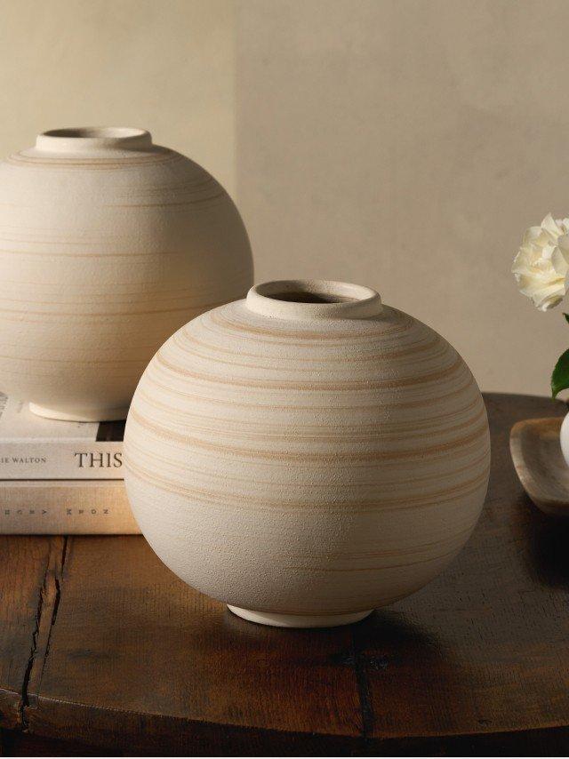 two vases on a table with a book and flowers