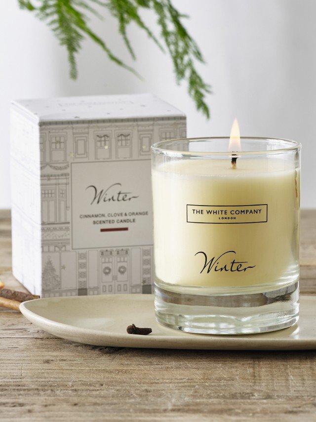 a candle sitting on a plate next to a box of chocolates