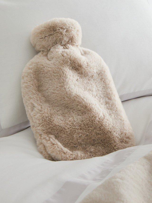 a hot water bottle on a bed with a white comforter