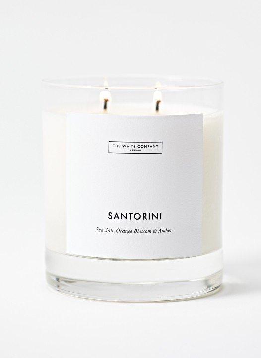 a white candle with a label that says santorini