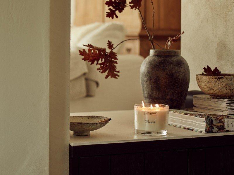 a candle on a table with a vase of flowers and books