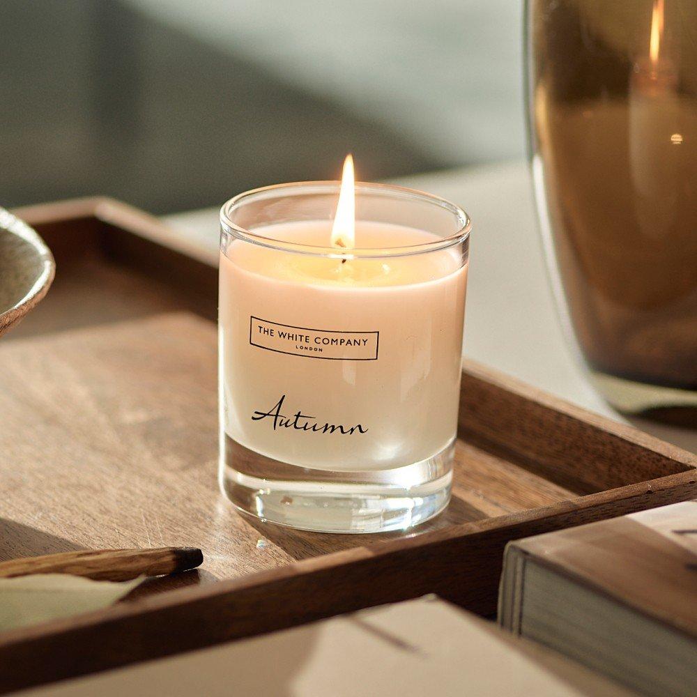 a candle sitting on a tray next to a book and a vase