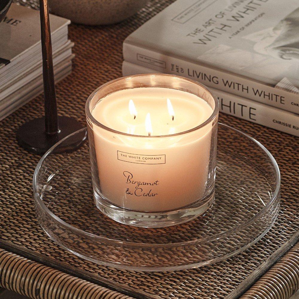 a candle sits on a glass table next to a book