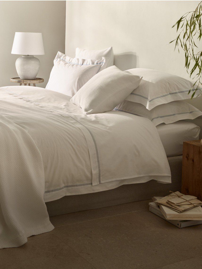 a bed with white sheets and pillows in a bedroom