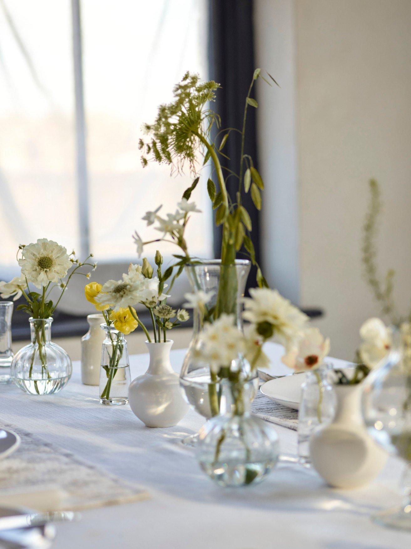 a table with vases of flowers on it with a window behind