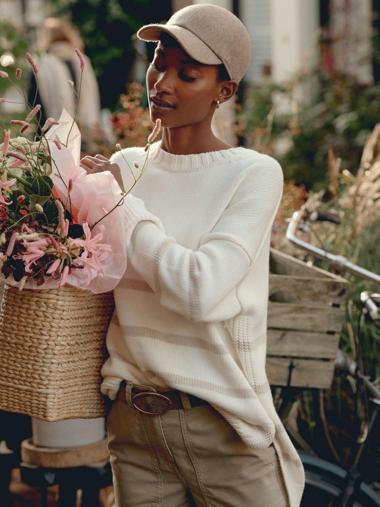 a woman holding a basket of flowers and a hat