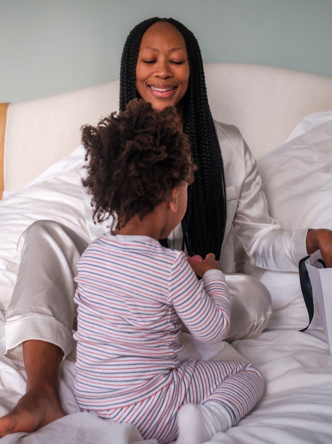 a woman sitting on a bed with a child on the bed