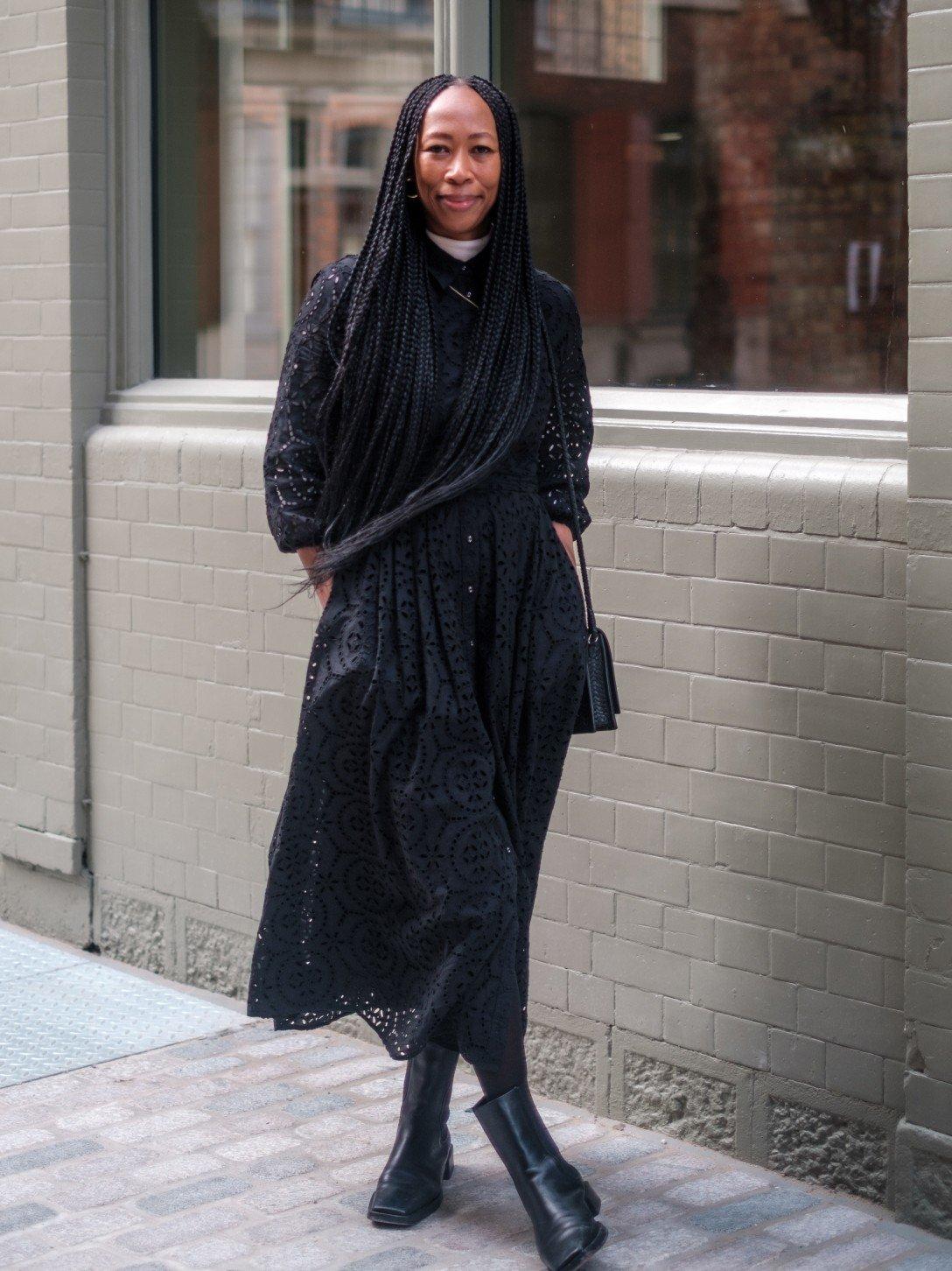 a woman in a long dress and boots standing on a sidewalk