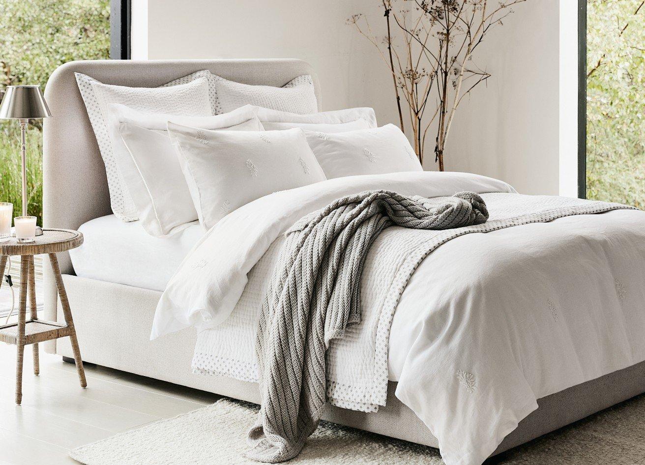 a bed with a white comforter and pillows in a bedroom