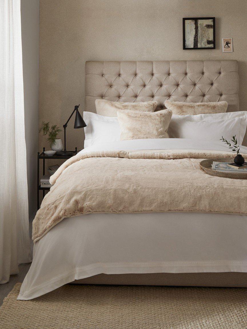 a bed with a white comforter and pillows in a bedroom