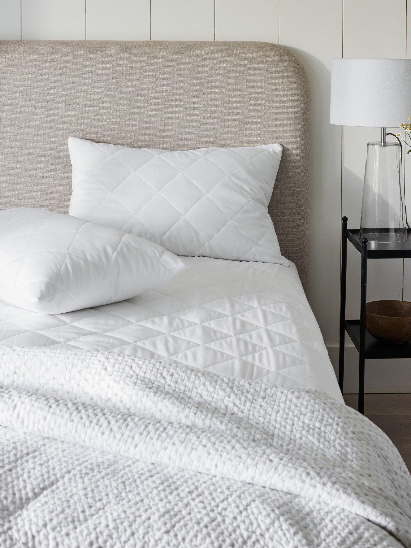 a bed with white sheets and pillows in a bedroom