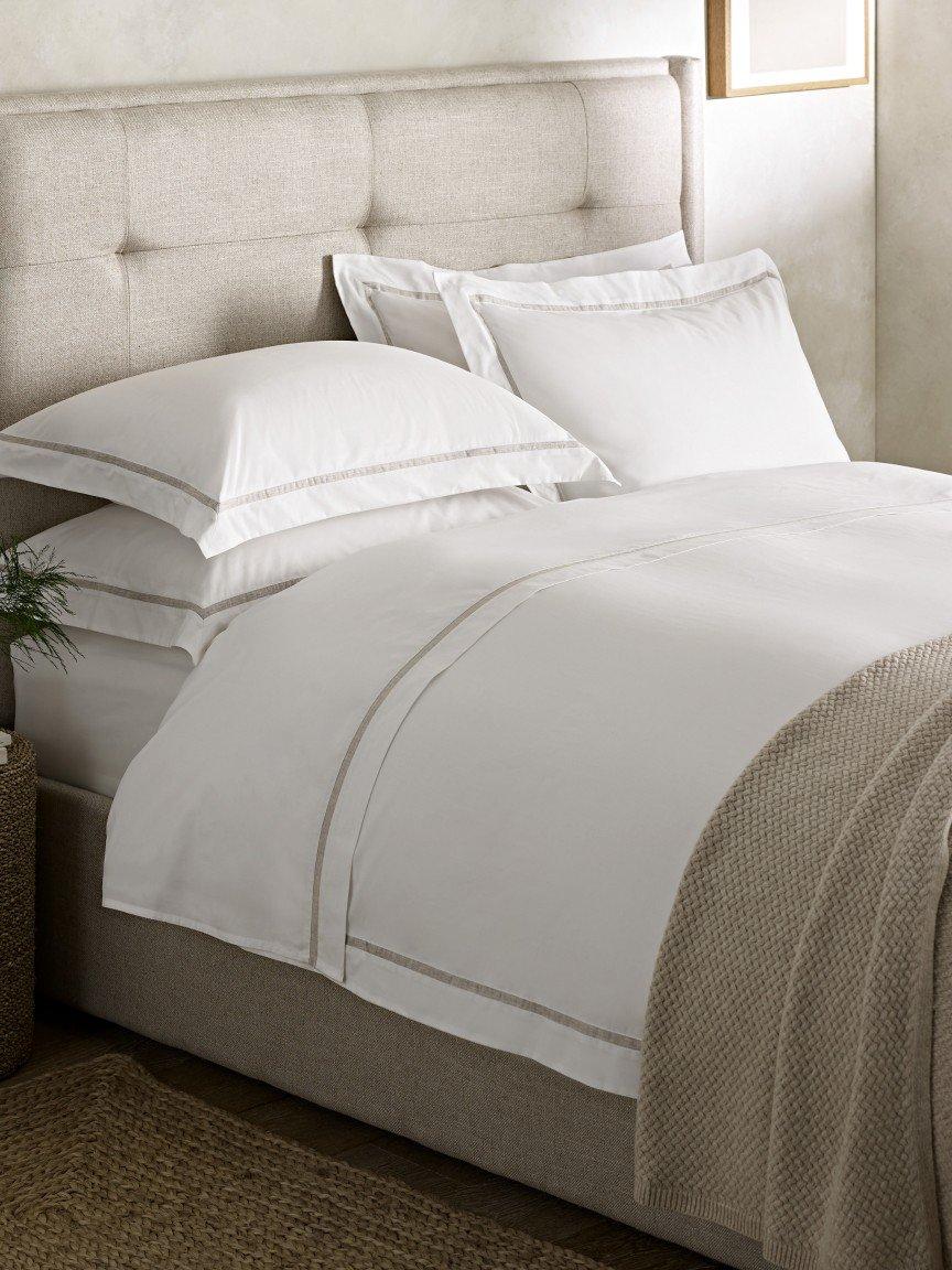 a bed with white sheets and pillows on a bed