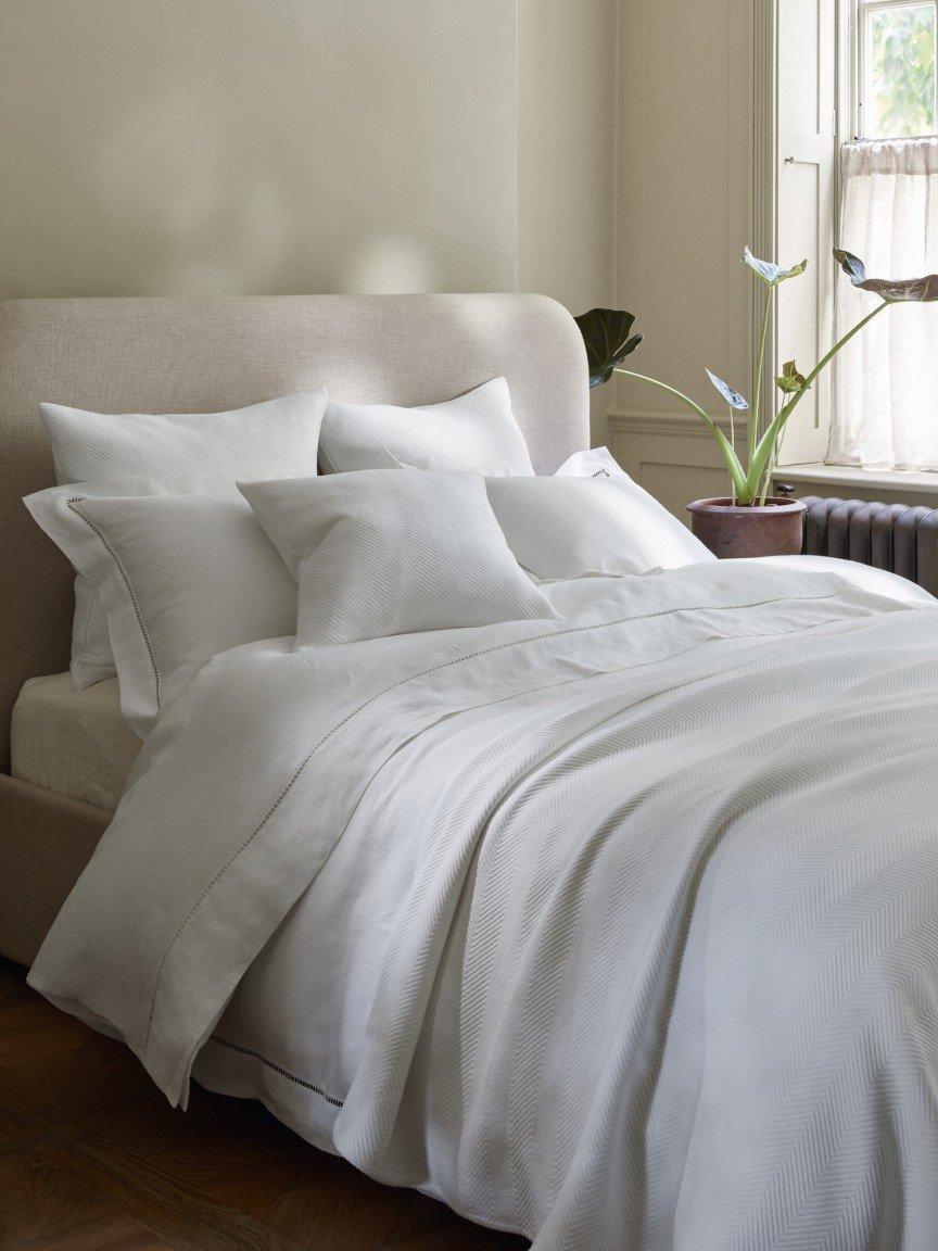 a bed with white sheets and pillows in a bedroom