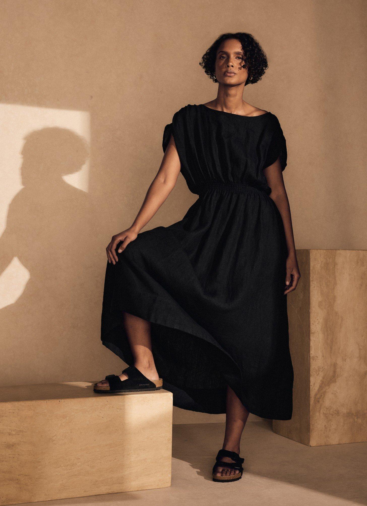 a woman in a black dress standing on a box