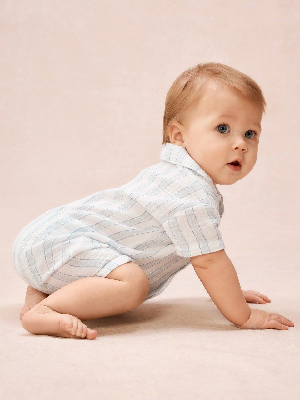 a baby crawling on the floor with a white shirt on