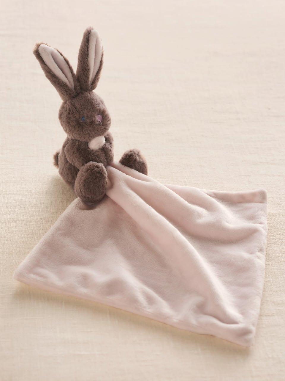 a stuffed bunny sitting on a pink blanket with a pink towel