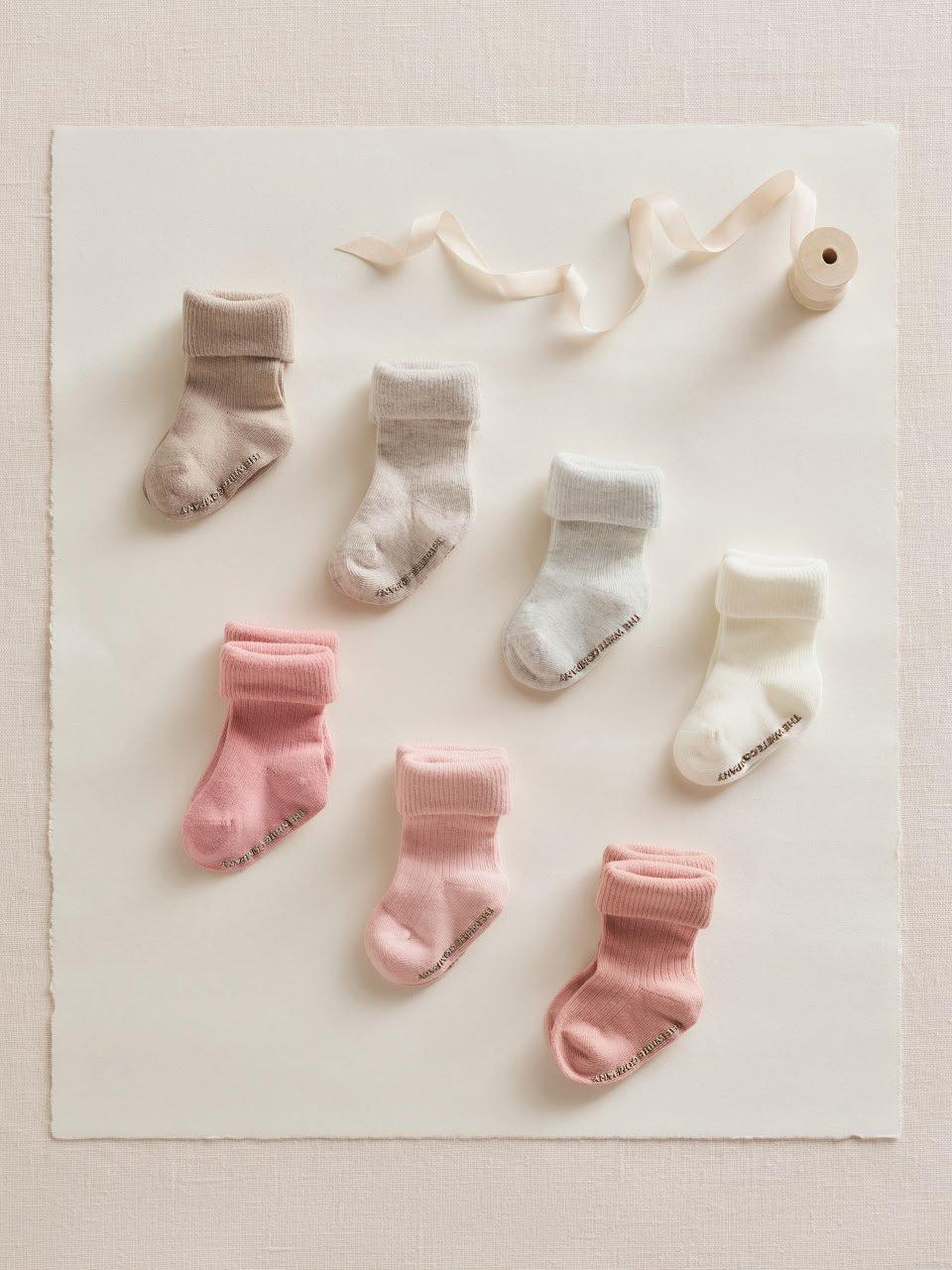 six pairs of baby socks are arranged on a white surface