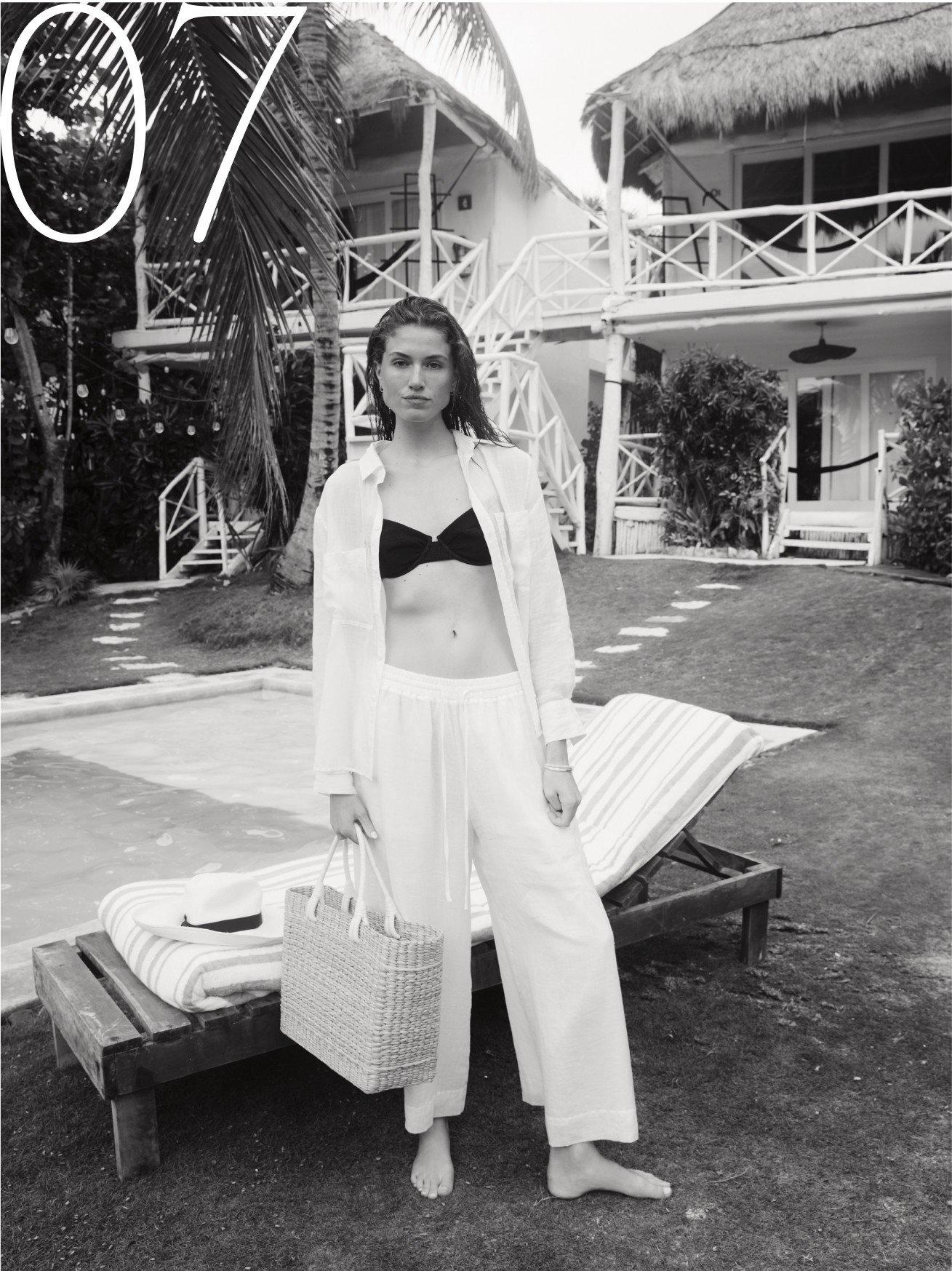 a woman in a bikini standing next to a lawn chair