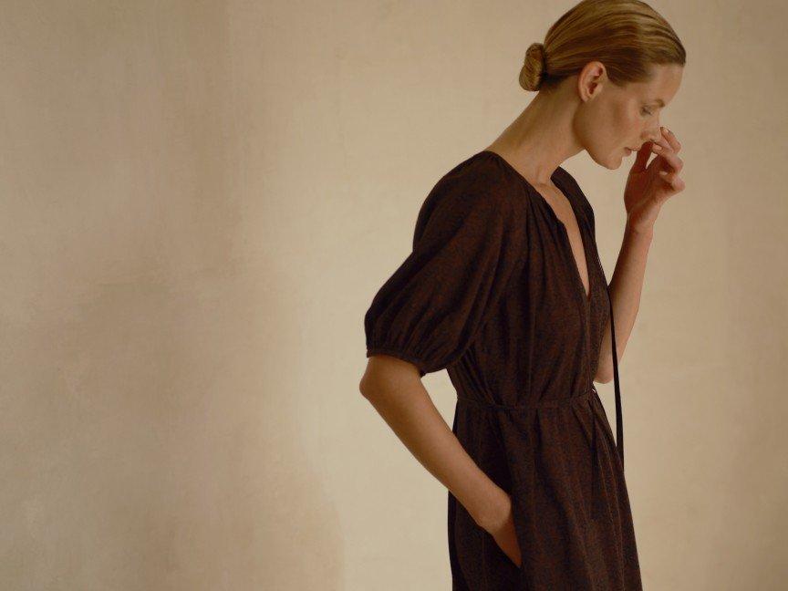 a woman in a brown dress standing in a room