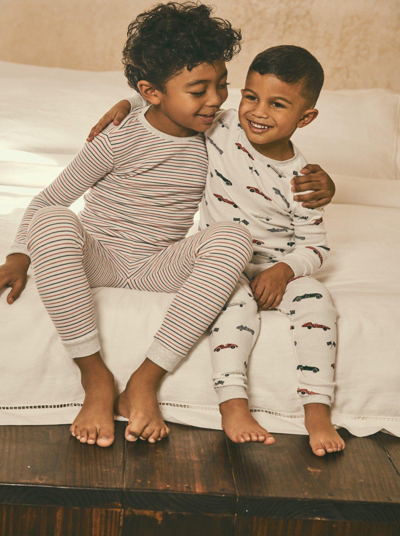 two young children sitting on a bed together in pajamas