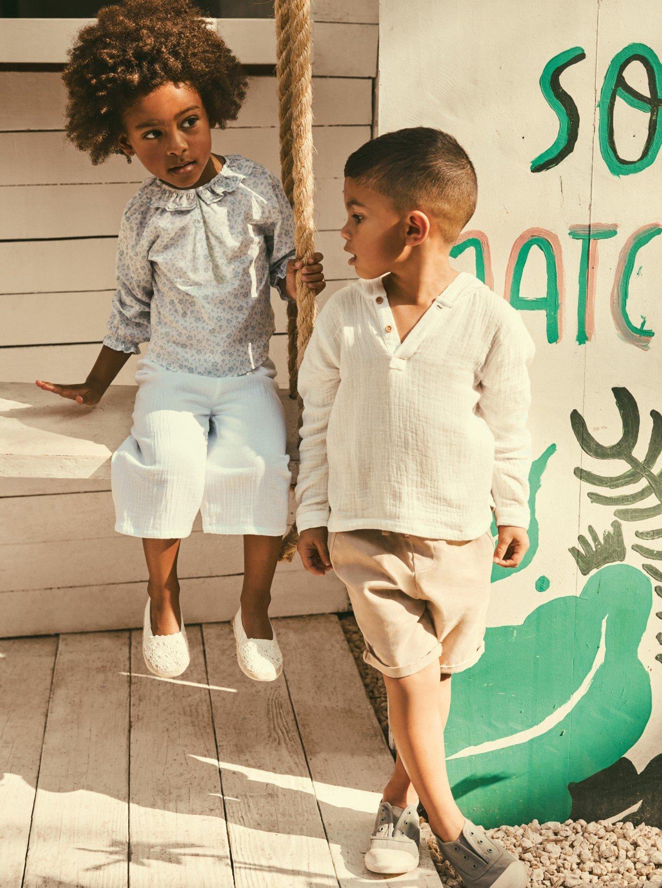 two children are standing next to each other on a swing