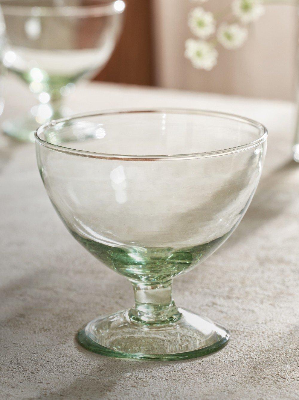 a glass bowl sitting on a table with a flower vase