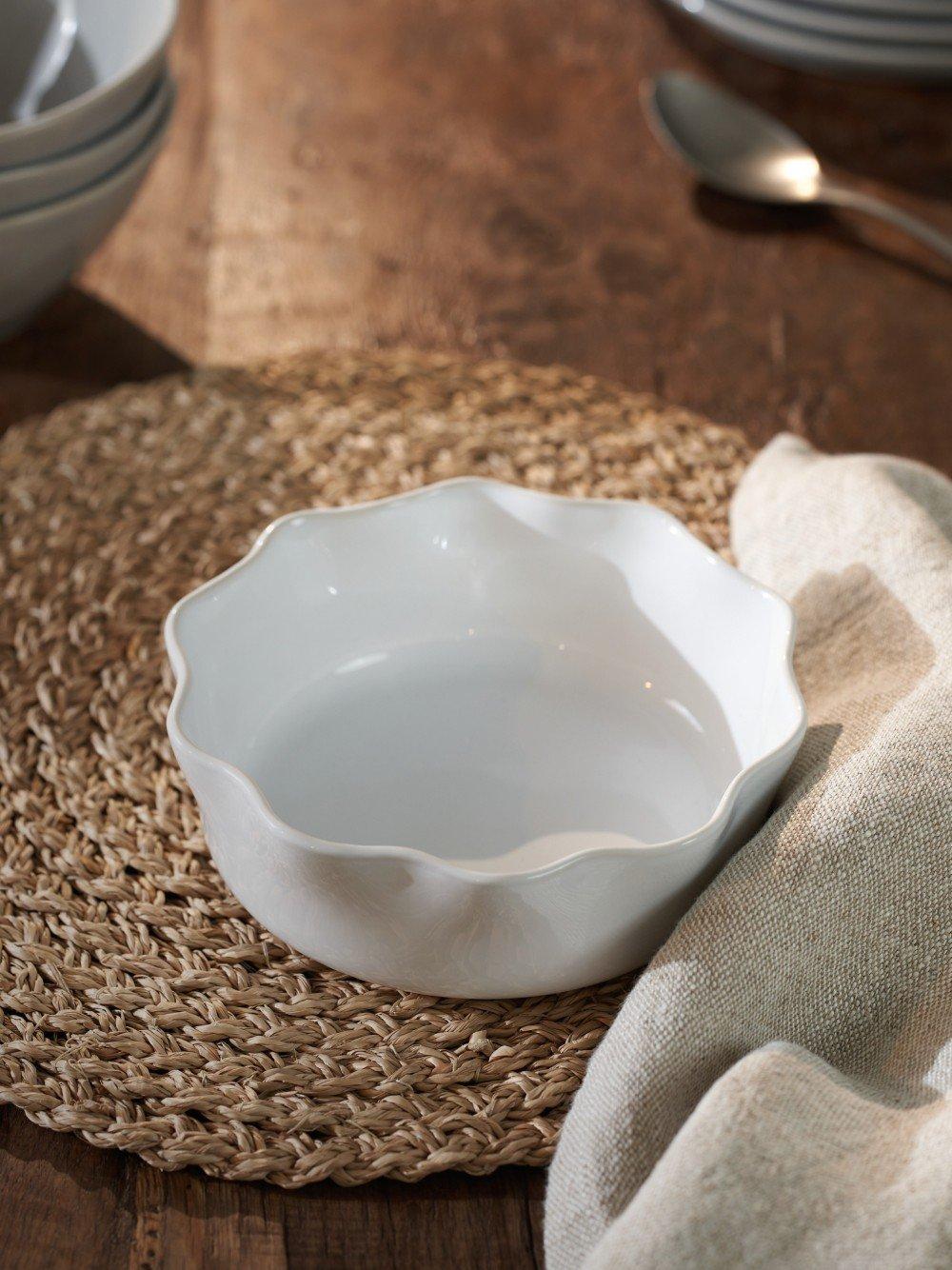 a white bowl sitting on a table with a placemat