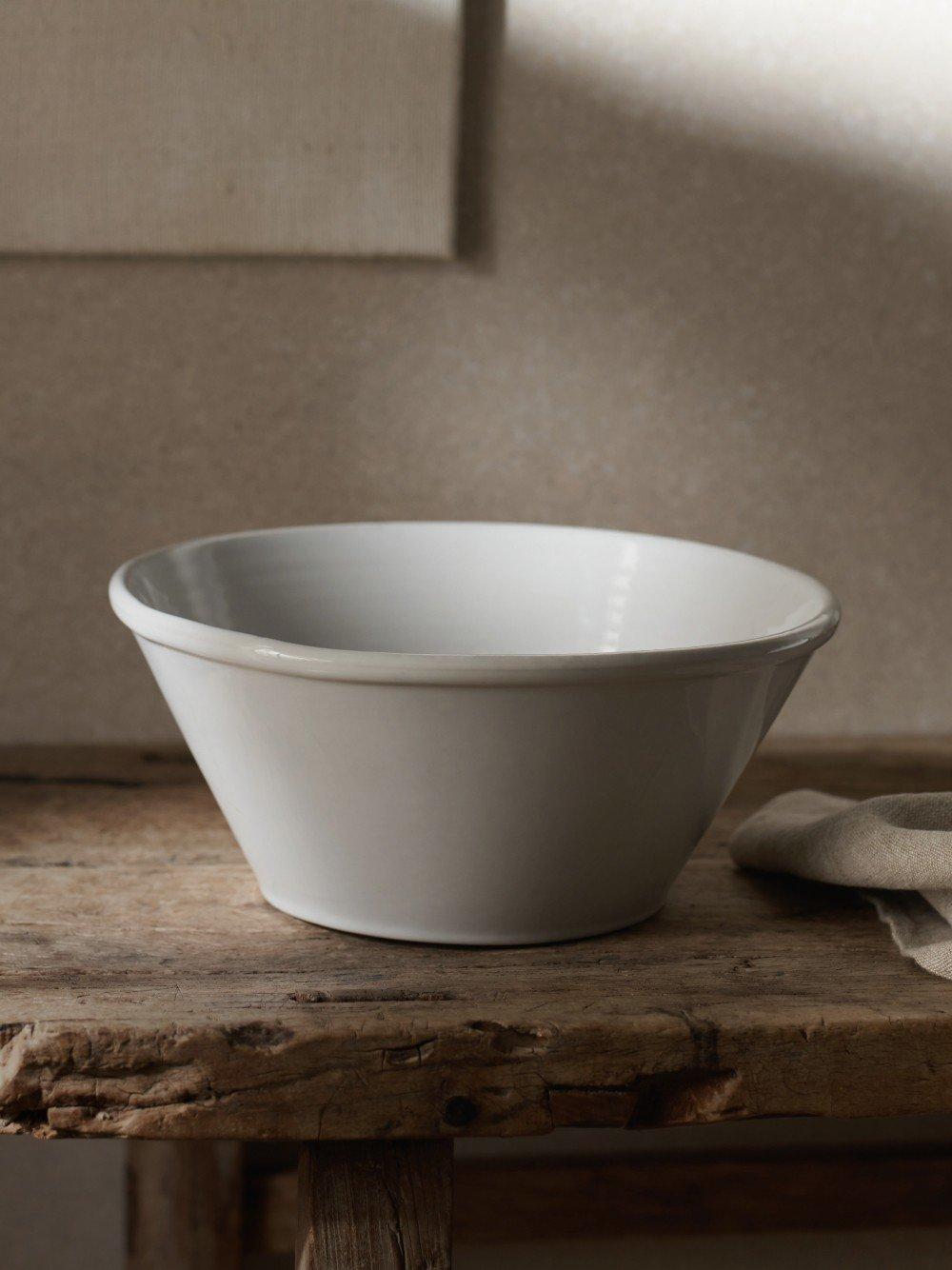 a white bowl sitting on a wooden table next to a towel