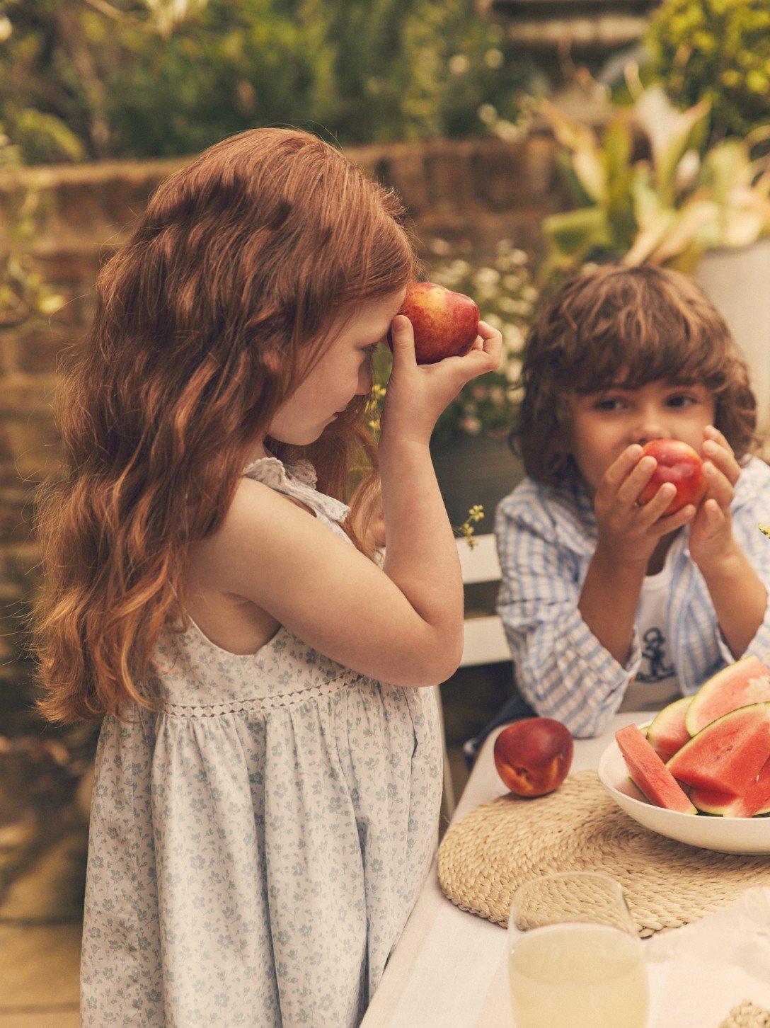 two children eating watermelon at a table outside